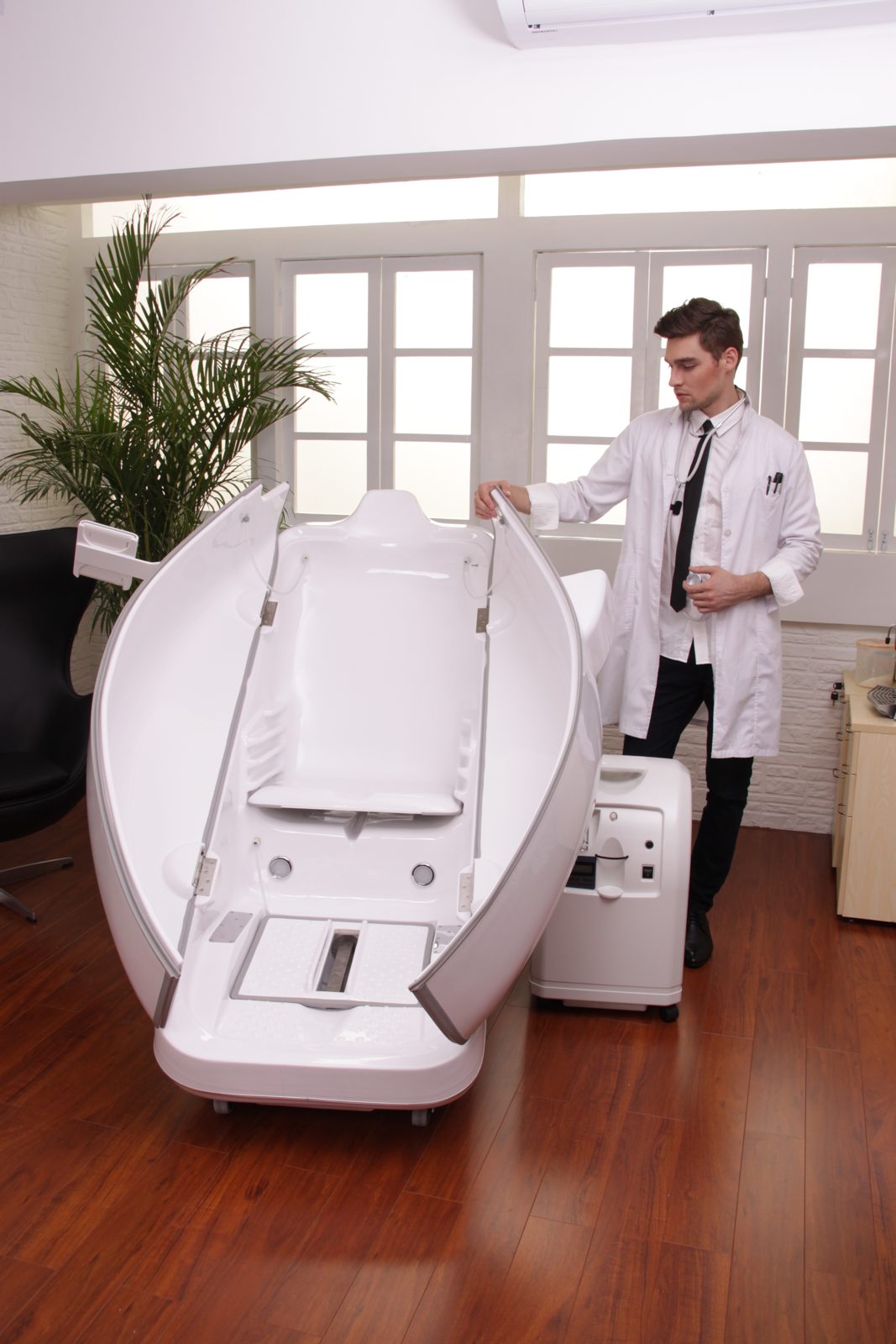 Practitioner standing beside an open HOCATT chamber in a treatment room